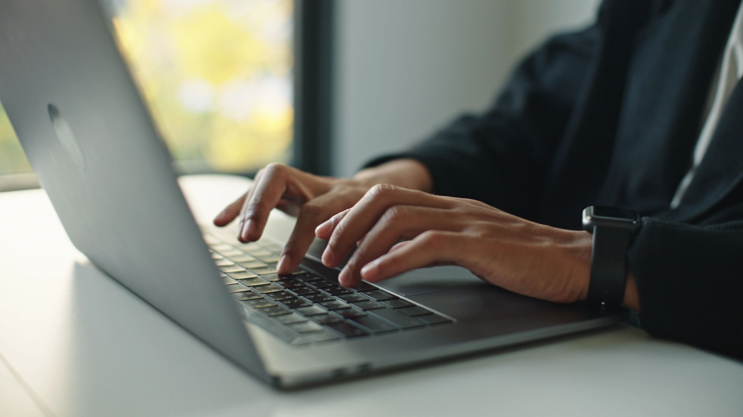 Close-up of hands typing on a laptop keyboard